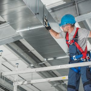 Professional Heating and Cooling Technician Worker Finishing Newly Assembled Air Vent Shaft. Air Climate Control and Filtering in Commercial Building.